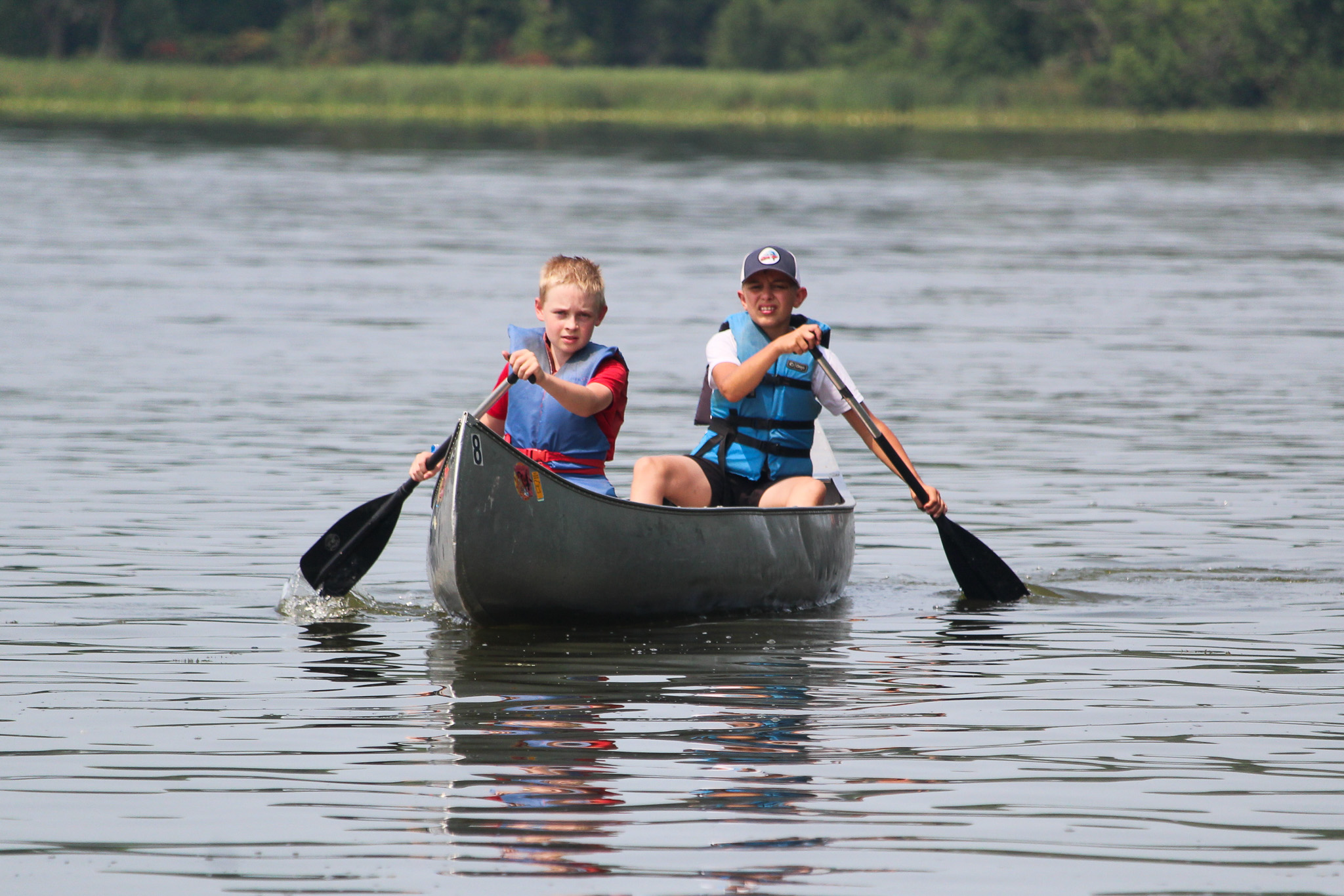 Two boys paddle a canoe